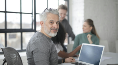 Hombre mirando a cámara en una reunión con compañeros  