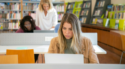 Chica joven rubia estudiando en biblioteca