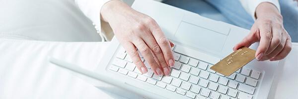 Manos sobre el teclado de ordenador con tarjeta crédito