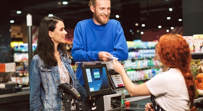 Pareja en el supermercado hablando con la cajera