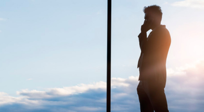 Hombre mirando por la ventana y hablando por teléfono