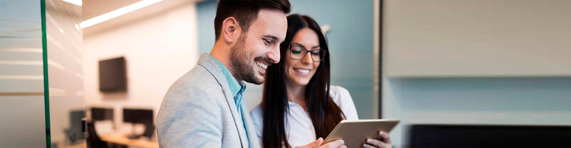 Cash Pooling - Hombre de traje sonriendo junto a una mujer de gafas sonriendo en oficina