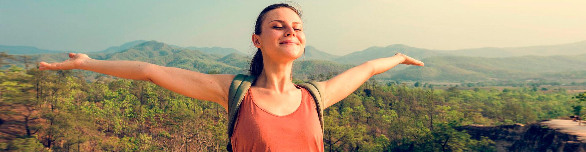 Préstamo Personal - Una chica joven con los brazos abiertos sonriendo en el monte