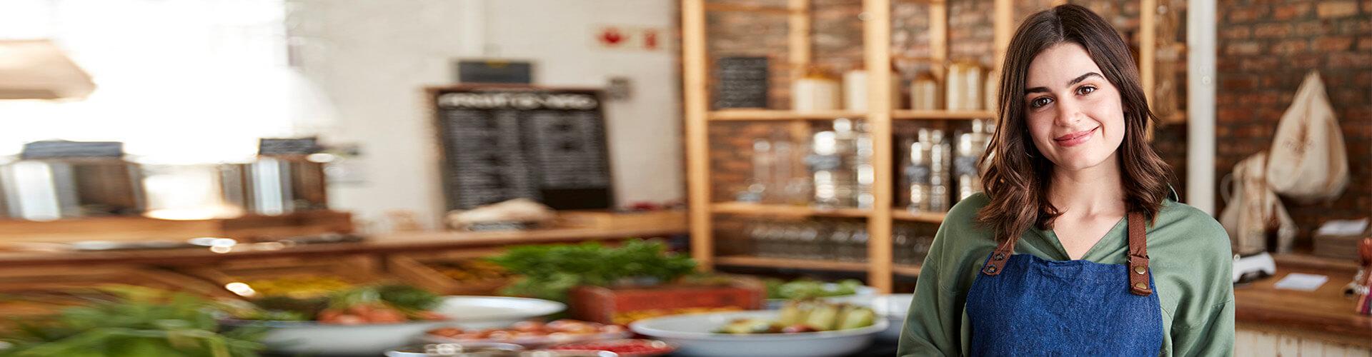 Mas seguros para autonomos - Dueña de un negocio de comida con delantal sonriendo a la camara