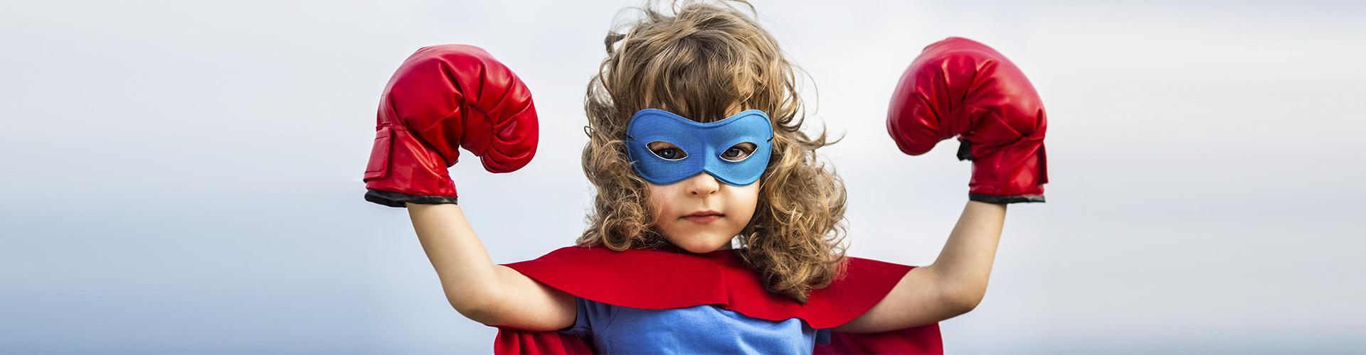 Programa En Marcha Infantil - Niño moreno con un disfraz de superman con un antifaz y guantes de boxeo mientras sonrie