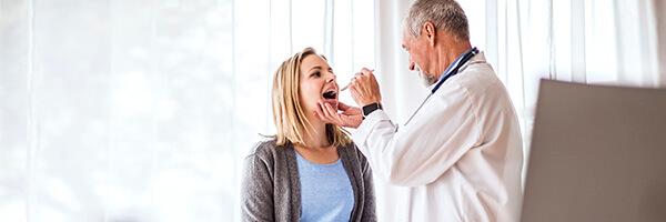 Seguro de Salud - Doctor senior examinando a una joven mujer en su consulta médica Seguro de Salud - Doctor senior examinando a una joven mujer en su consulta médica