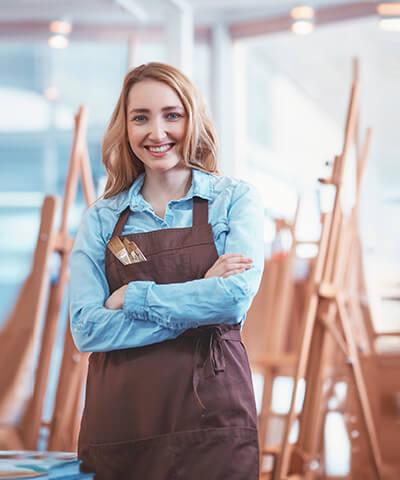 Ventajas para Autónomos - Una joven artista con los brazos cruzados sonriendo en un estudio